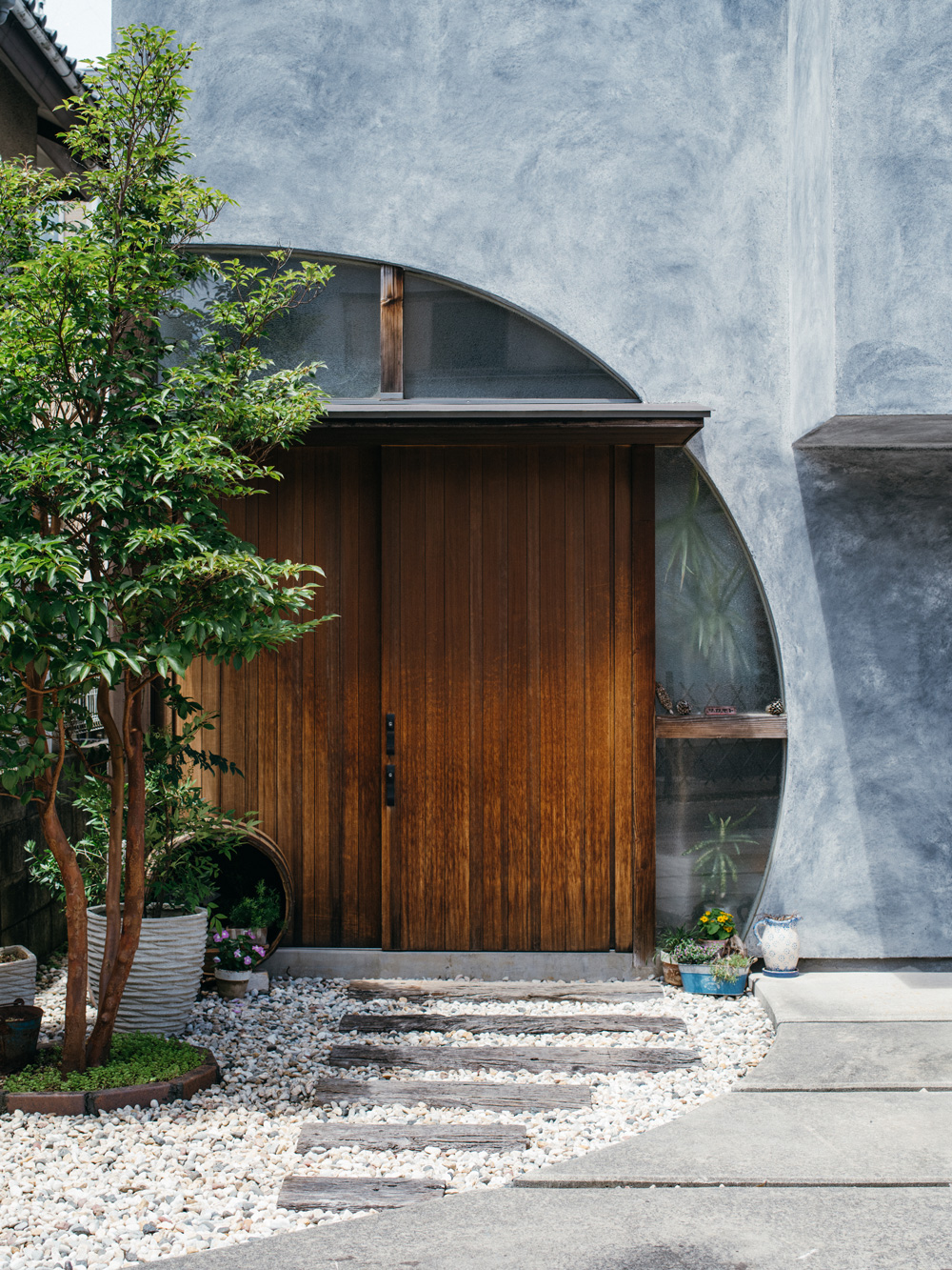 『モルタル＋墨』の外壁の家の敷石とアール入口